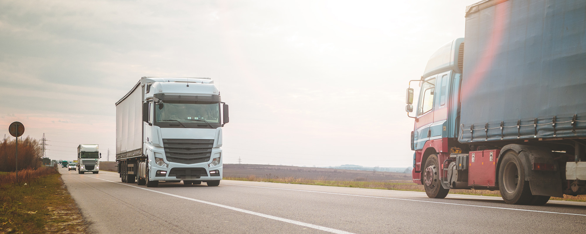 Arriving white truck on the road in a rural landscape at sunset