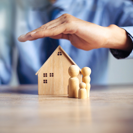 person holding their hand over a model of a house