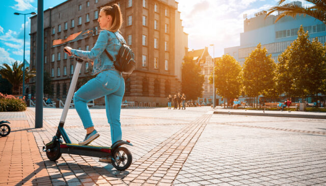 Scooter nature. Kick electric city bike using from business woman. Electric scooters for public share standing outside