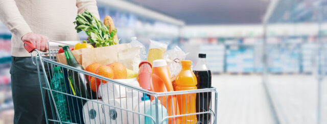 Man pushing a full trolley at the supermarket, grocery shopping concept